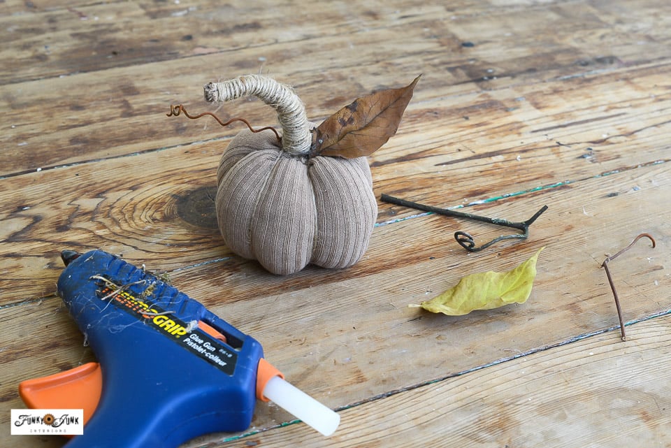 hot gluing real leaves and grapevine tendrils to a fabric pumpkin made from a sock
