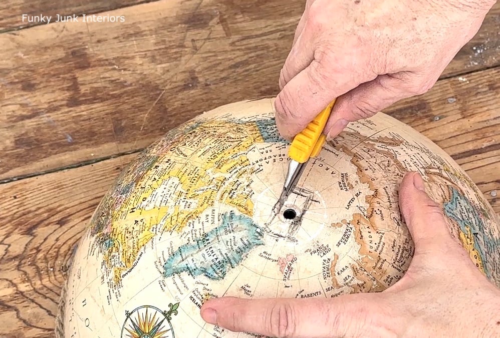 cutting into a globe to create an upcycled globe light
