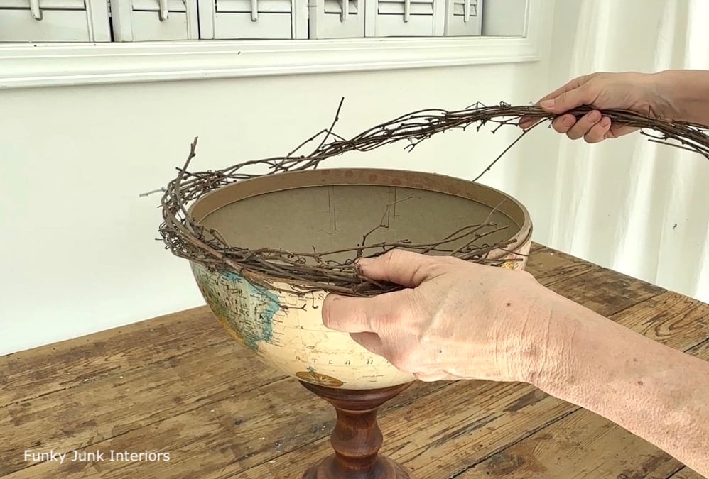 gluing grapevine garland onto an upcycled globe bowl