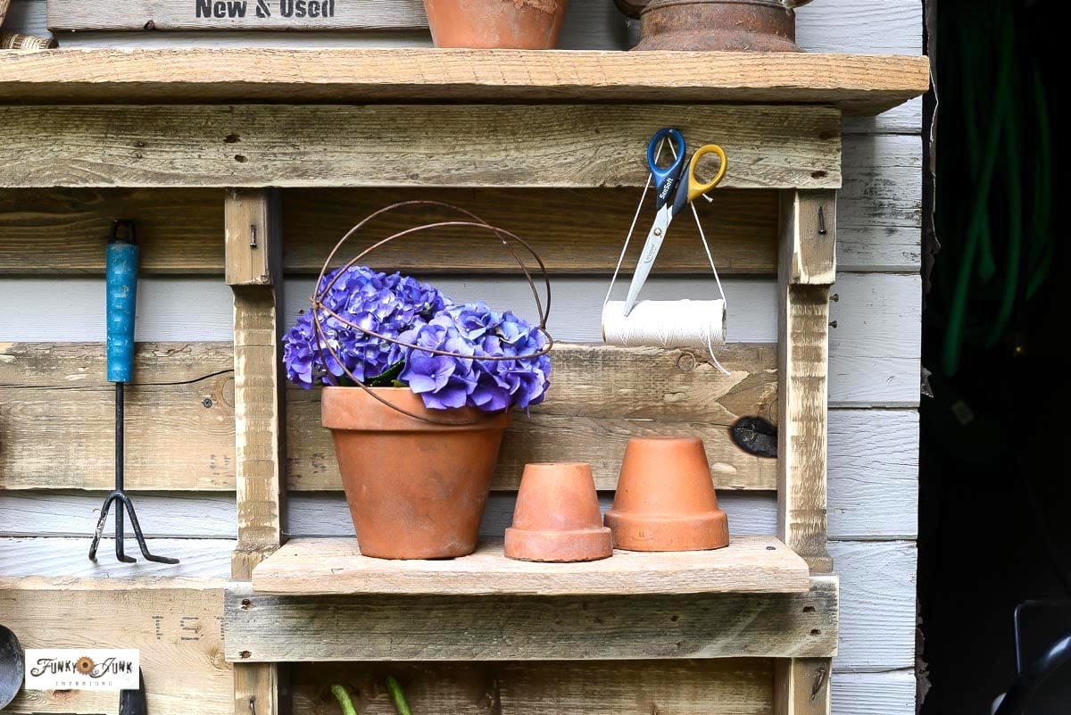 clay pots, flowers and string hanging on a pallet yard tool organizer