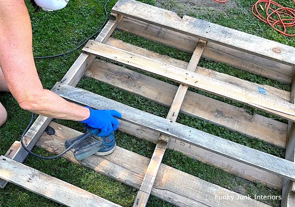 sanding a pallet to make a yard tool organizer