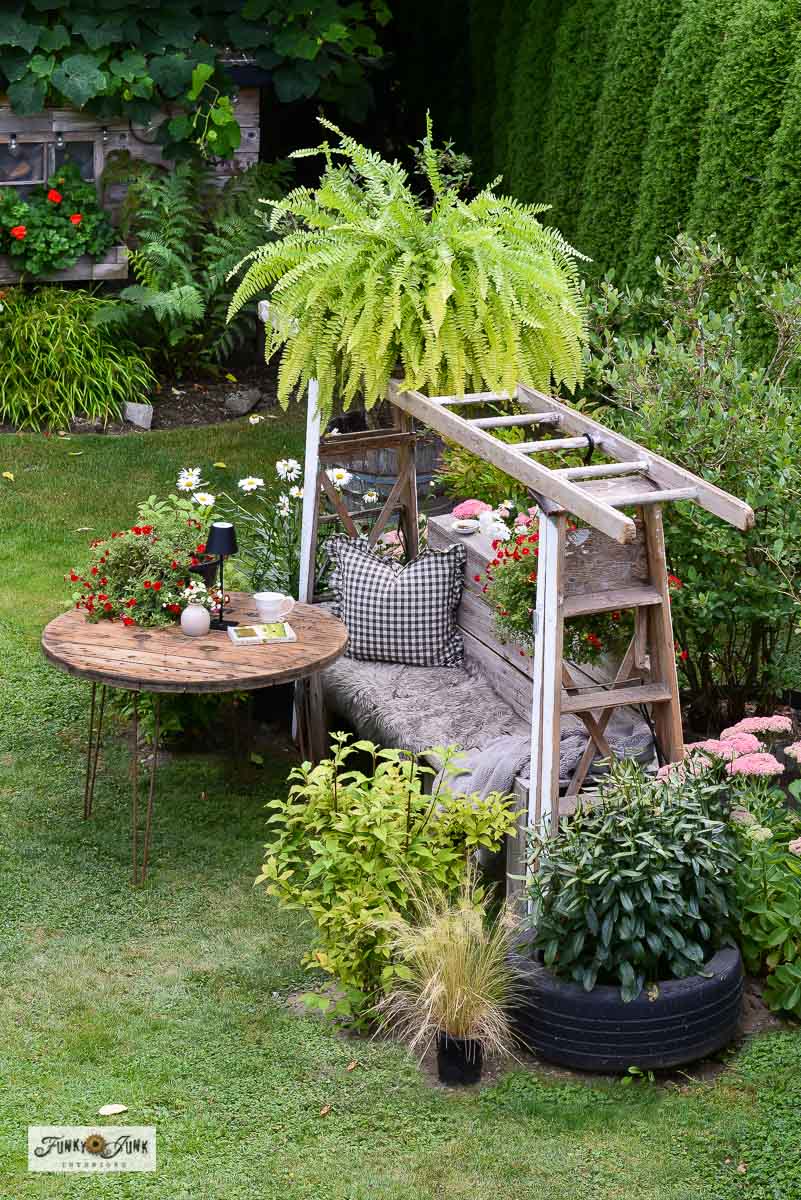 whimsical ladder garden arbor above a wooden garden bench