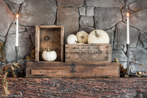 pumpkins and antique welcome fall crates on a fireplace mantel
